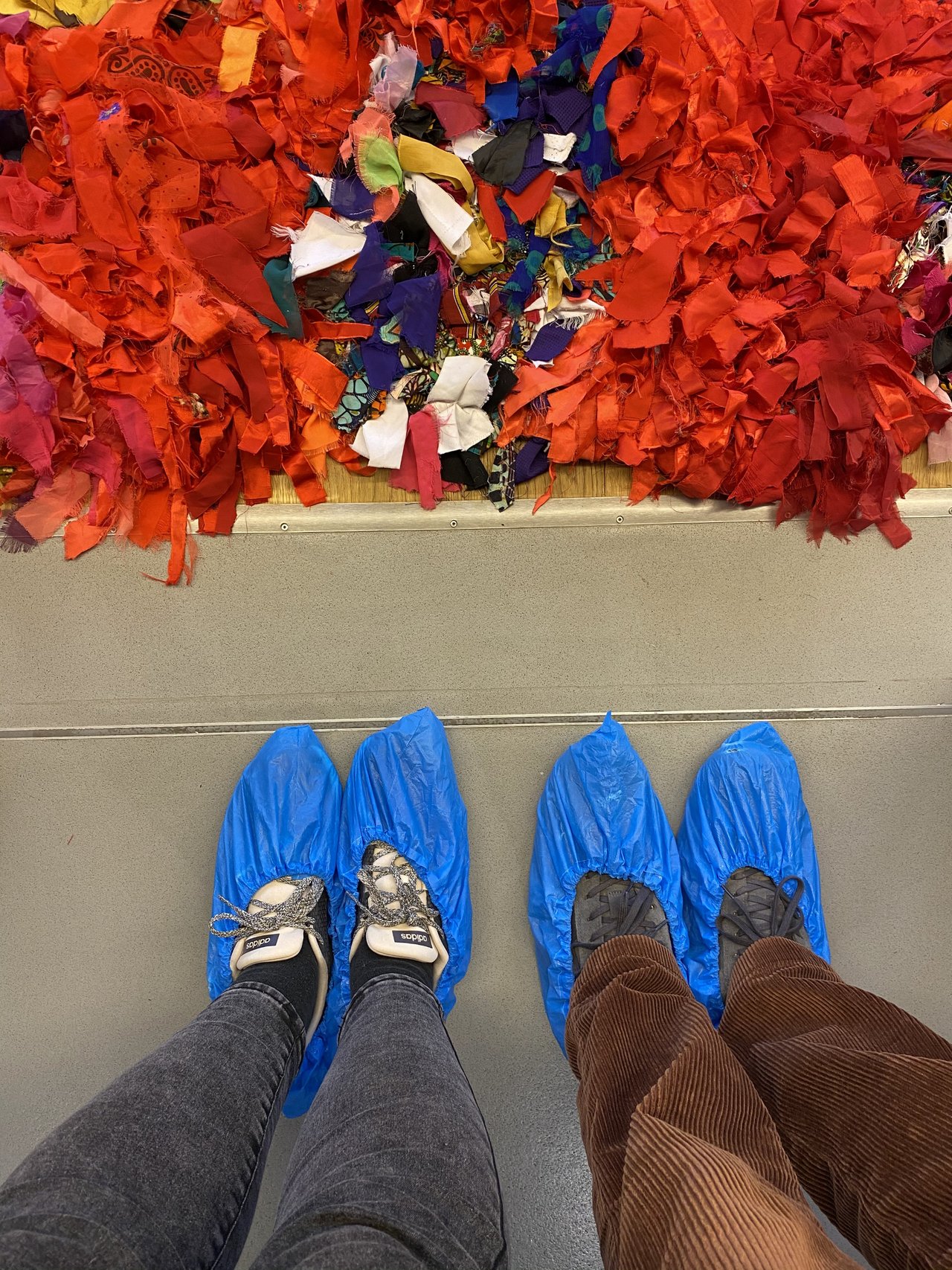 our feet clad in protective covers in front of a red carpet