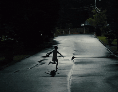 a shadow of a person running down a dark street