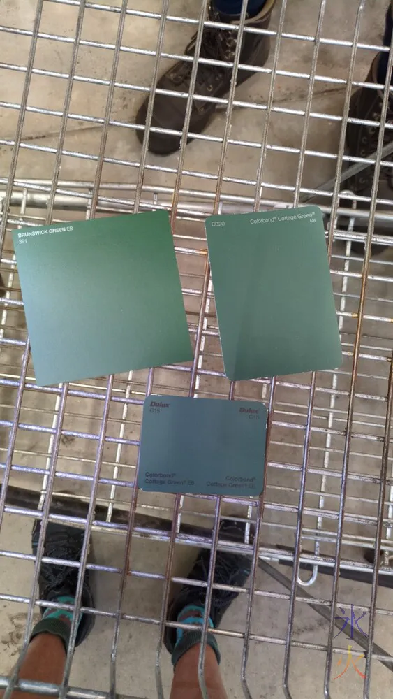 two Cottage Green and one Brunswick Green paint swatches in a Bunnings trolley