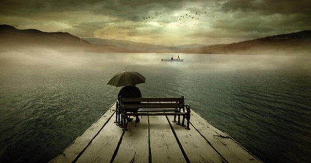 man sitting rain lake bench