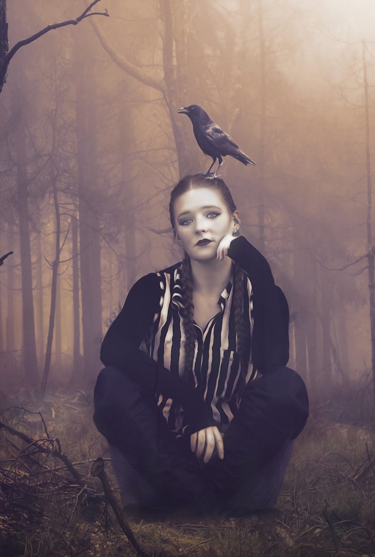 A girl sits with crossed legs with a crow on her head.