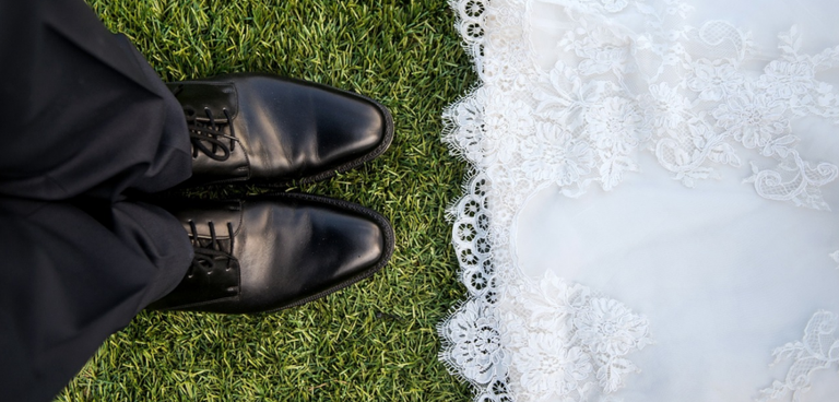 Looking down at a bride's dress and groom's shoes