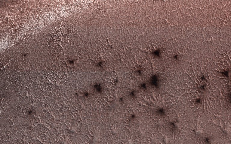 This image from NASA's Mars Reconnaissance Orbiter, acquired May 13, 2018 during winter at the South Pole of Mars, shows a carbon dioxide ice cap covering the region and as the sun returns in the spring, "spiders" begin to emerge from the landscape.