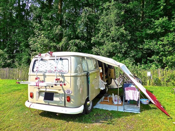 Van is camped with folding chairs and a tarp awning making everything comfortable.