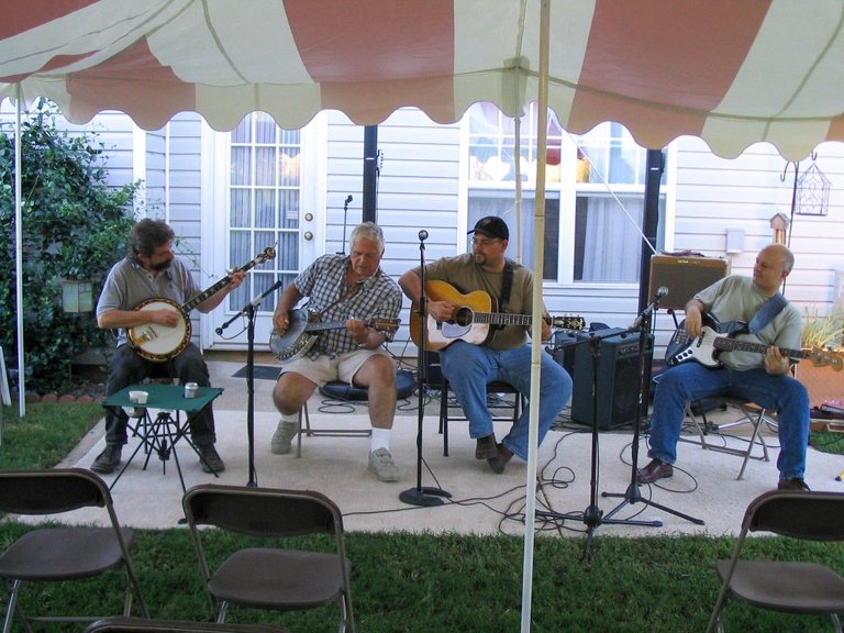 A bluegrass band playing live, with two banjos, a flattop guitar and an electric bass guitar. 
