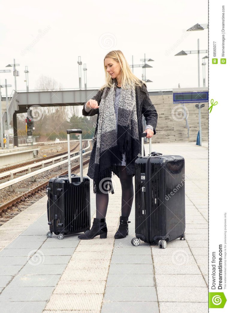 mujer-que-espera-con-las-maletas-en-la-estación-de-tren-68565077.jpg