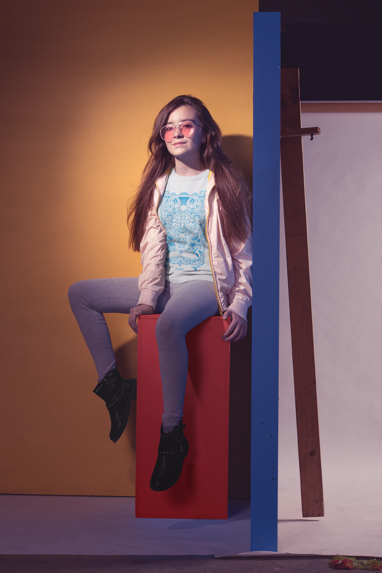 cool-little-girl-wearing-a-t-shirt-mockup-sitting-on-a-colored-structure-a19588.png