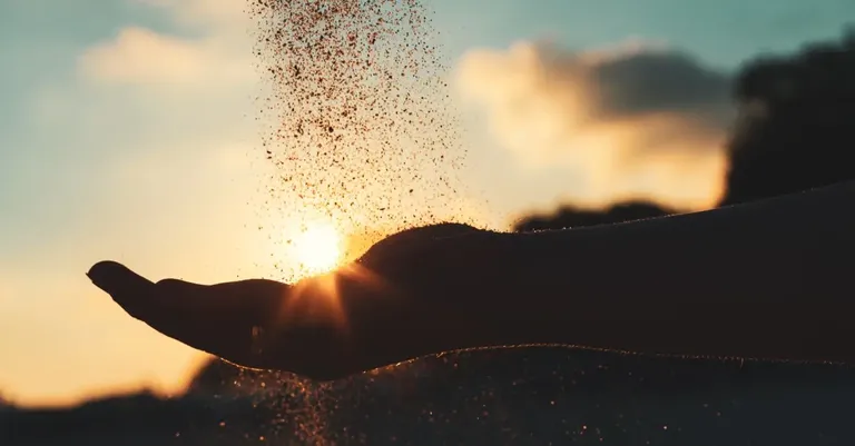 15093-sand-pouring-through-open-palm-to-signify-hol.webp