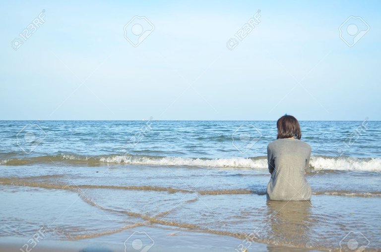 20395930-the-girl-is-sitting-alone-at-the-beach-and-looking-through-the-sea.jpg