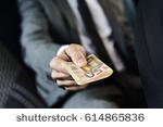 stock-photo-a-young-caucasian-man-in-an-elegant-gray-suit-sitting-in-the-back-seat-of-a-car-offers-a-wad-of-614865836.jpg