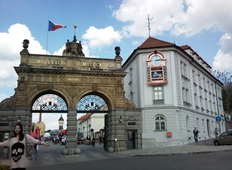 Vstupni_brana_plzenskeho_pivovaru_s_japonskou_turistkou_a_pivnim_orlojem.jpg