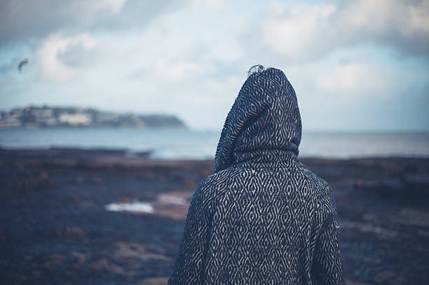 young-woman-in-hooded-coat-walking-on-beach-picture-id507202326.jpg