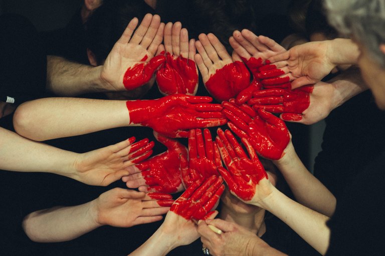 Many hands together and formed, with red paint, into a heart