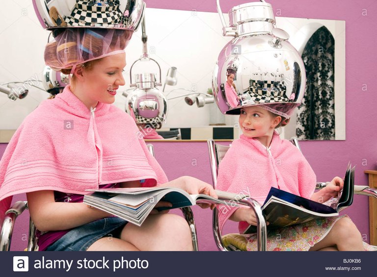 young-woman-and-little-girl-sitting-under-hair-dryers-at-hair-salon-BJ0KB6.jpg