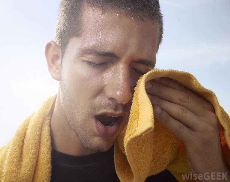 man-sweating-while-dabbing-face-with-orange-towel.jpg