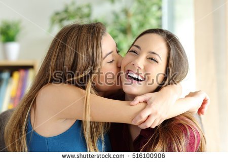 stock-photo-affectionate-girl-kissing-her-happy-sister-or-friend-in-the-living-room-at-home-with-a-homey-516100906.jpg