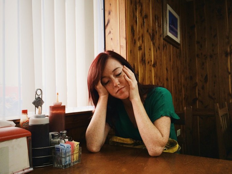 a-tired-young-woman-at-a-restaurant-holds-her-face-in-her-hands_t20_nmGx3P.jpg