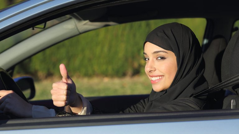 happy-arab-saudi-woman-driving-a-car-with-thumb-up-picture-id491243781.jpg