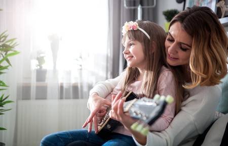 96956859-mom-with-her-daughter-playing-electric-guitar-together-at-home-happy-family.jpg