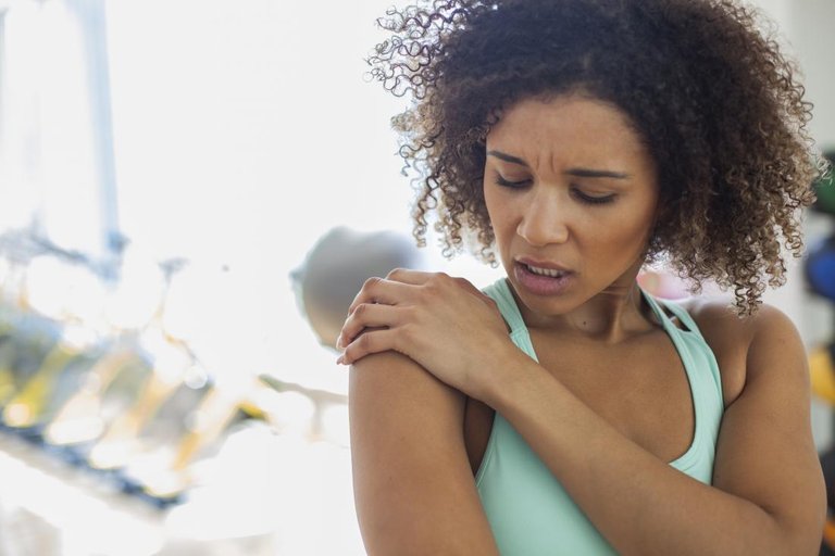 Woman with shoulder subluxation holding shoulder joint in pain.