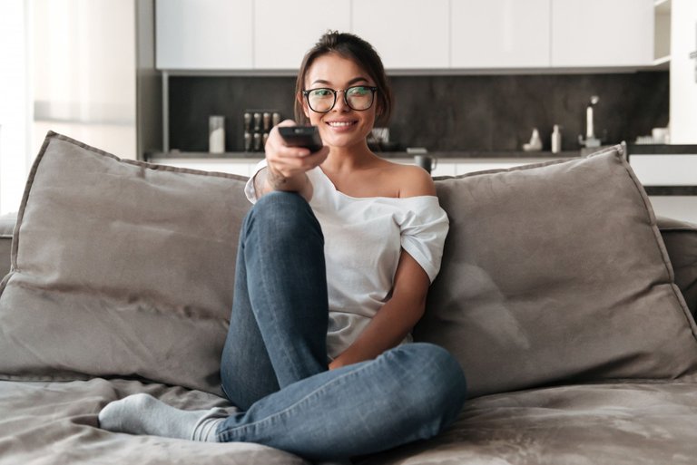 happy-young-woman-sitting-on-sofa-at-home-watch-tv.jpg