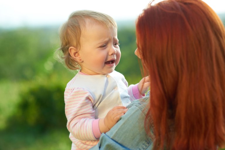 crying-daughter-sitting-mother-s-hands-during-sunny-day-field-young-mom-trying-calm-down-little-baby-talking-her-woman-having-red-hair-wearing-jeans-shirt.jpg