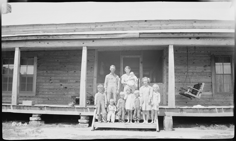 Mc_Cracken,_Early,_family_on_front_porch_of_their_home_-_NARA_-_280936.png