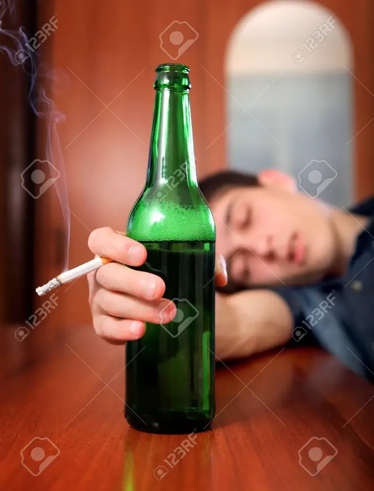 47757234-tired-young-man-sleep-with-bottle-of-the-beer-and-cigarette-at-the-home.webp