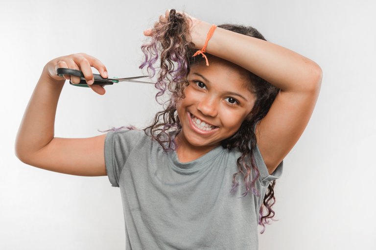 smiling-girl-cutting-her-hair-with-scissors.jpg