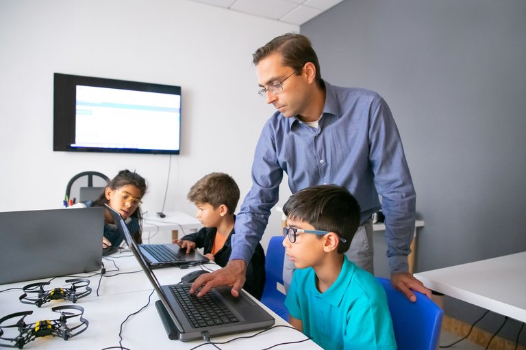 pupils-doing-task-laptops-focused-teacher-monitoring-them.jpg