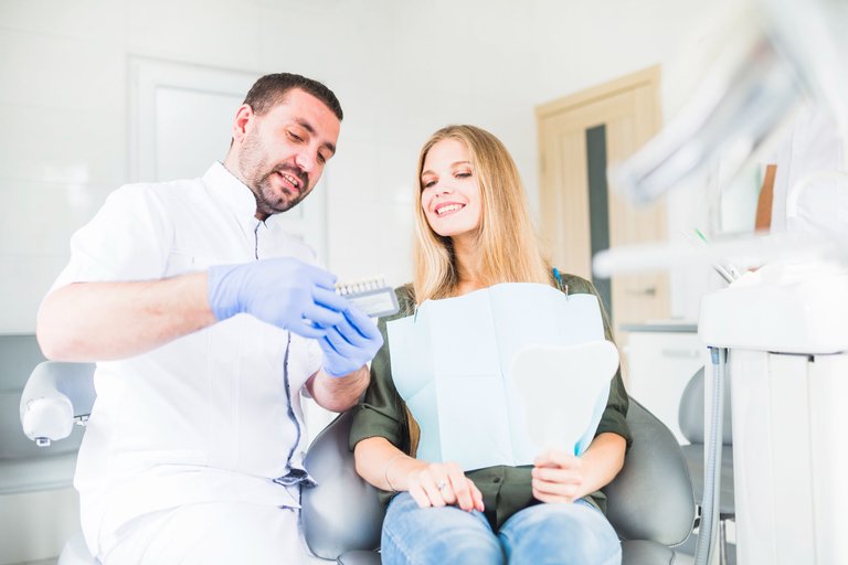 dentista-asistiendo-paciente-femenino-feliz-al-elegir-tono-color-sus-dientes.jpg