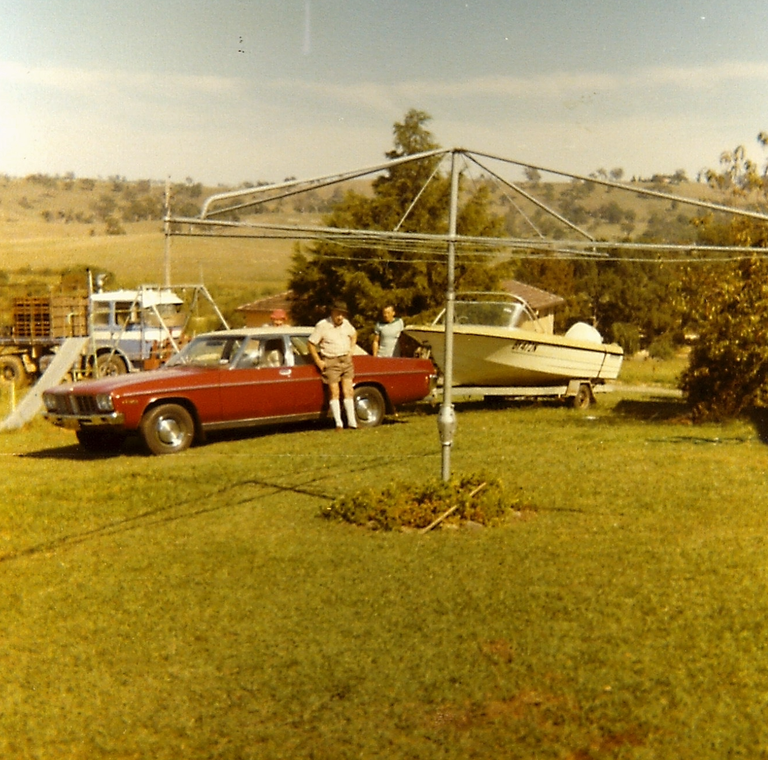 GRANDPA AND DAD STANDING AT THE STATESMAN WITH THE BOAT ON THE BOACK AND THE MAN IN THE BACKGROUND.png