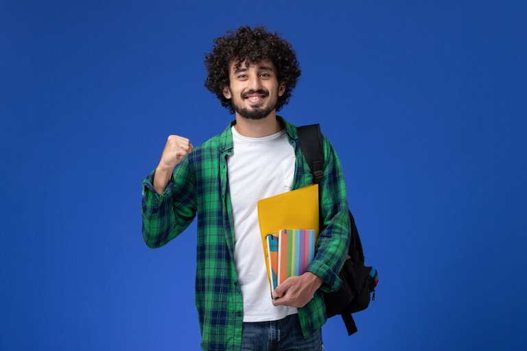 front-view-male-student-wearing-black-backpack-holding-copybooks-files-blue-wall.jpg