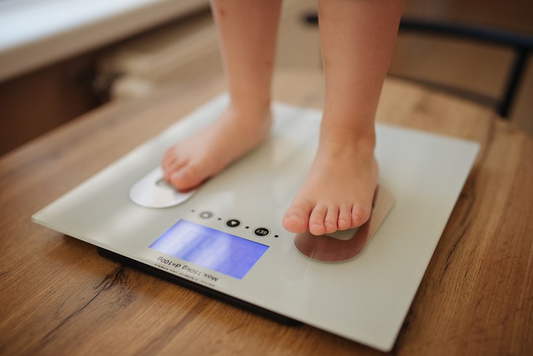 Girl_stands_and_weighs_himself_on_white_modern_electronic_smart_scale_-_51258015258.jpg