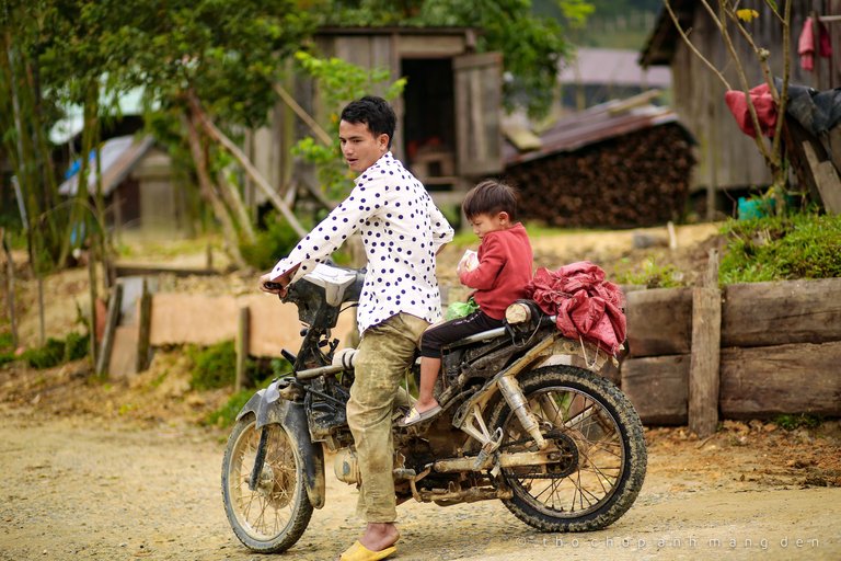 The father is driving his child to school on his old motorbike in the morning.