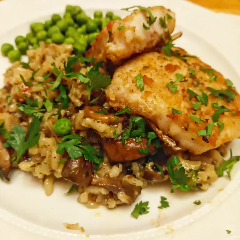 Pan-fried hake on a bed of risotto with peas and parsley