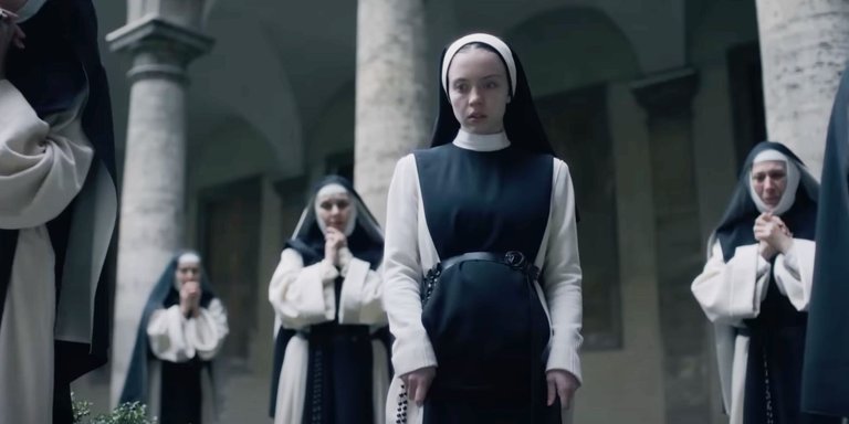 sydney-sweeney-s-cecilia-looking-downward-in-shock-while-nuns-pray-behind-her-in-immaculate.jpg
