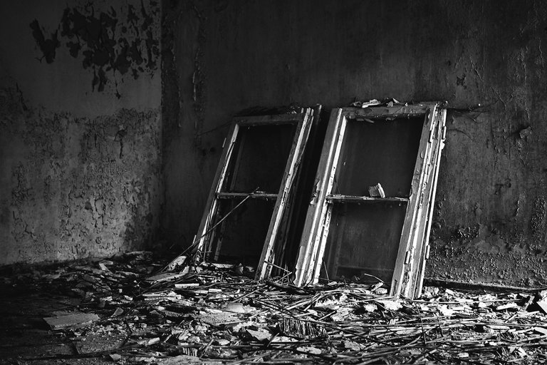 grayscale-shot-of-window-frames-placed-on-messy-floor-in-an-old-house.jpg