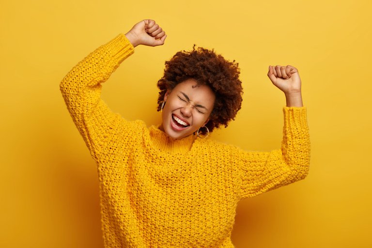 joyful-afro-woman-raises-arms-tilts-head-dressed-casual-knitted-jumper-laughs-from-happiness-celebrates-victory-isolated-yellow.jpg
