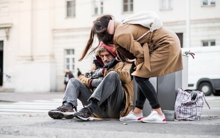 115295263-mujer-joven-dando-dinero-al-mendigo-sin-hogar-sentado-en-la-ciudad-.jpg