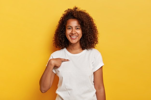 smiling-cheerful-dark-skinned-girl-points-herself-shows-mockup-space-white-t-shirt-happy-being-picked-models-against-yellow-wall-carefree-delighted-young-afro-woman-asks-who-me_273609-27741.jpg