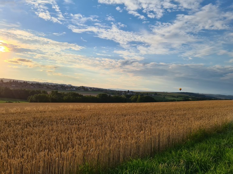 Vue sur une mongolfière, le coucher de soleil, la campagne et la ville de Carrouge depuis Ferlens