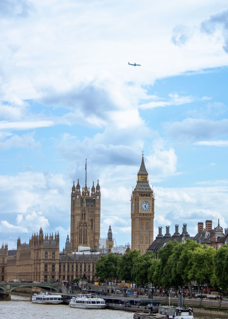 Big Ben and Houses of parliament with blue cloudy skies and a plane.jpg