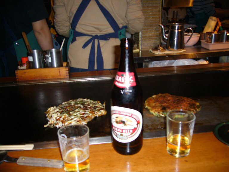 442 - Dinner in Osaka - Okonomiyaki on left⬅️ is mine. I went back on my next visit to Osaka, with my brother, and could not find this joint.  But I thought it was super famous. The staff all wear green aprons and I swear Anthony Bourdain went here on one of his trips to Japan. Anyone can give me a map pin to this joint, I'd truly appreciate it.