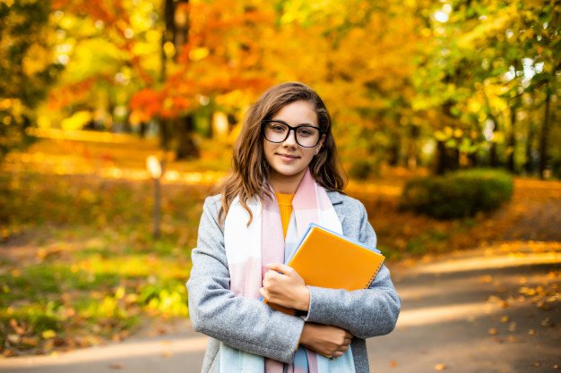 outdoorautumnportraithappysmilingteenagegirlwithcopybooks_231208152.jpg