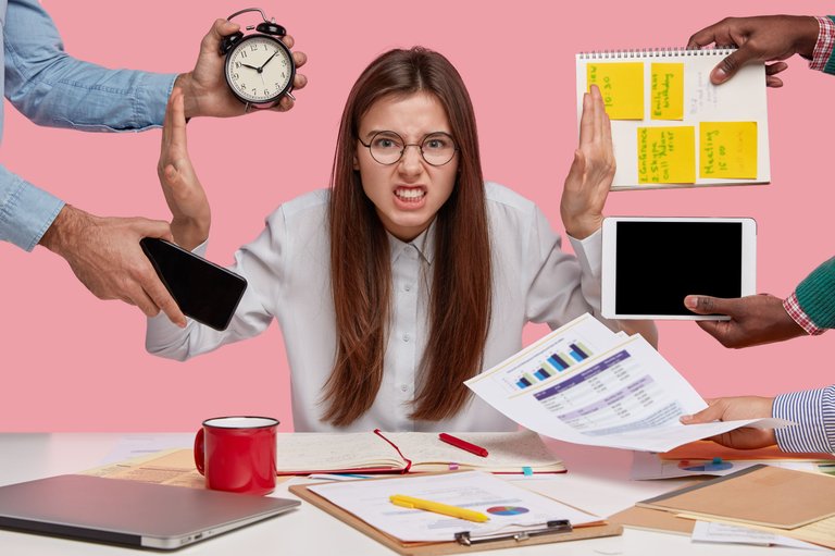 overworked-young-employee-refuses-all-things-frowns-face-annoyance-sits-desktop-with-paper-documents-notepad-isolated-pink-wall-female-worker-bothered-by-many-questions.jpg