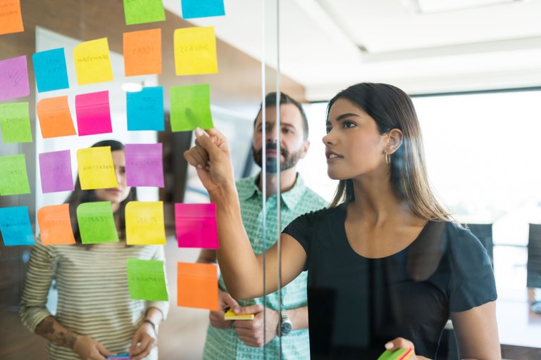 female-young-manager-discussing-adhesive-note-with-coworkers-office-meeting.jpg