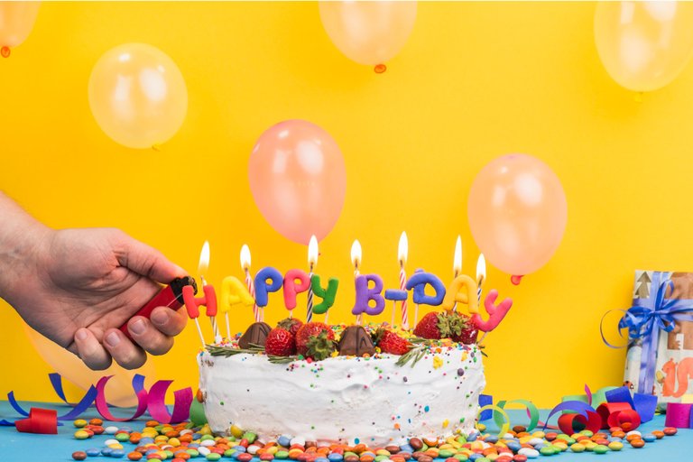 front-view-birthday-cake-hand-lighting-candles.jpg