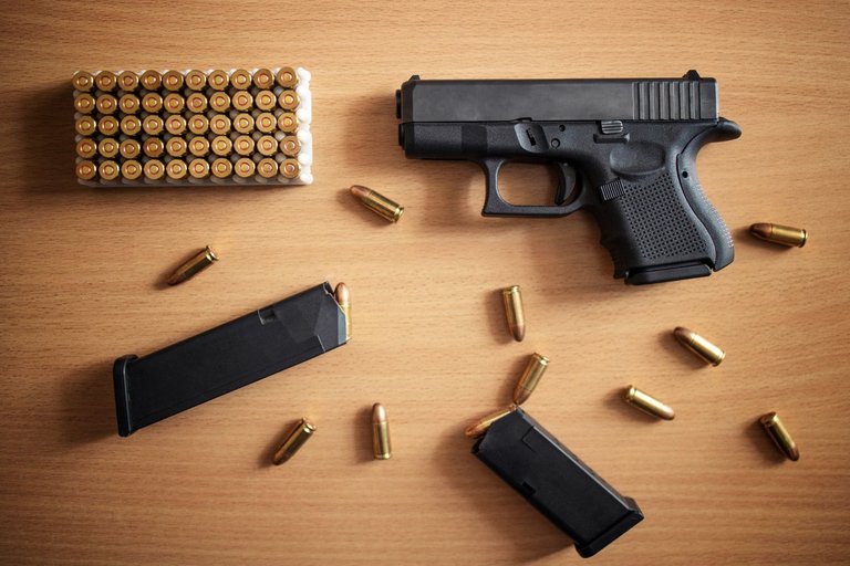 gun-with-box-ammunition-bullets-wooden-wall.jpg
