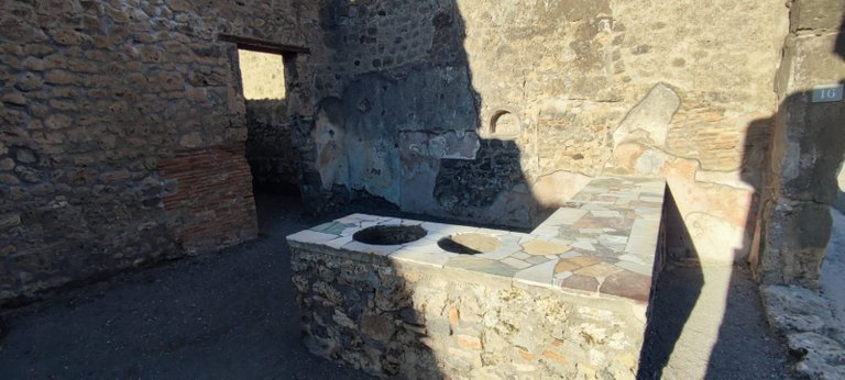 Kitchen in one of Pompeii's houses, with a large counter and "2-burner stove"